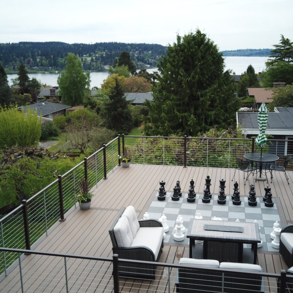 Finished deck with a lake and forest view, upscale outdoor seating, and a giant chess set